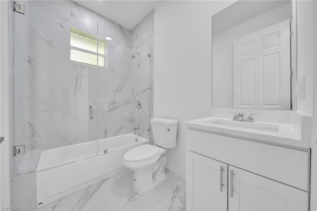 Full bathroom with shower / bath combination with glass door, vanity, and light marble finish flooring