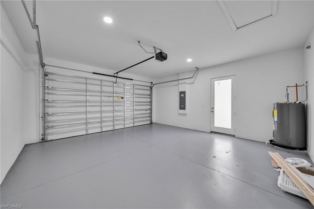 Garage featuring water heater, recessed lighting, electric panel, and a garage door opener