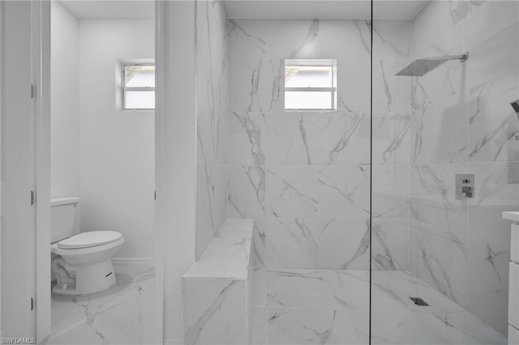 Bathroom with a marble finish shower and marble finish flooring