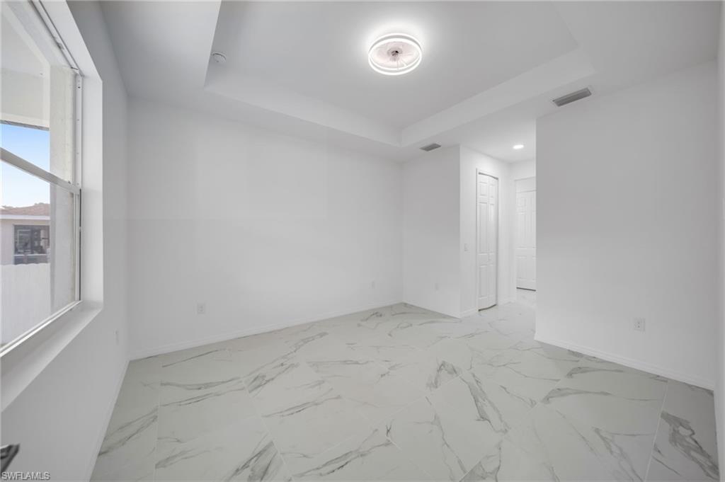 Unfurnished room featuring baseboards and a tray ceiling