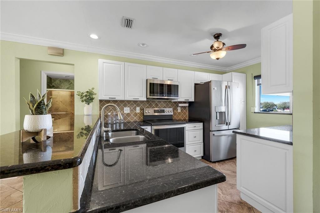 Kitchen featuring white cabinets, crown molding, granite countertops and stainless appliances