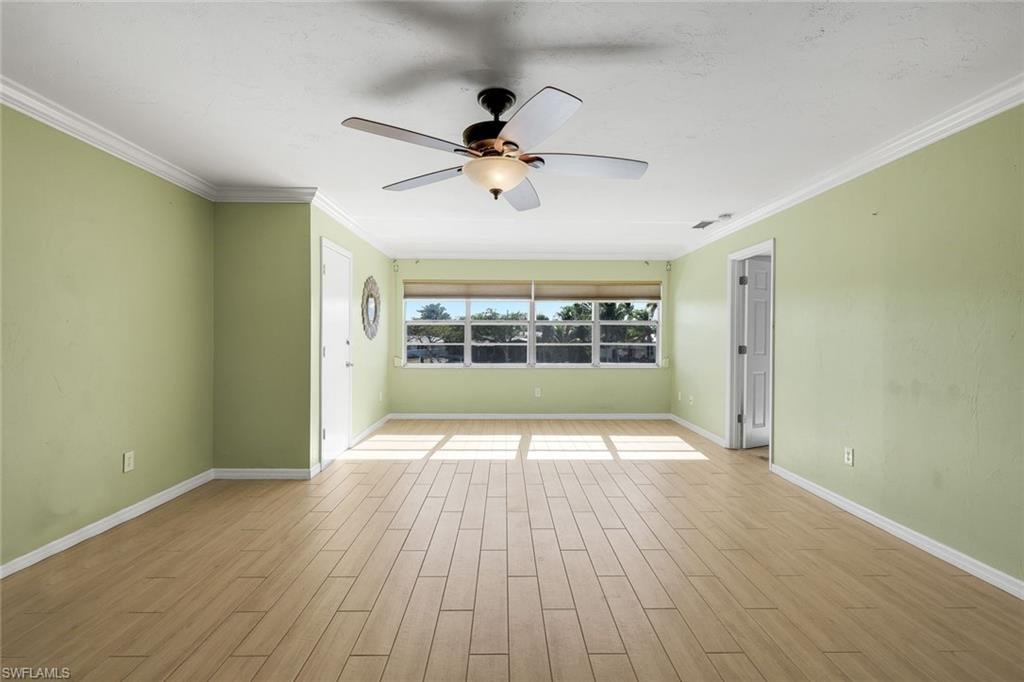 Spare room with wood tiled floors, ornamental molding, and ceiling fan
