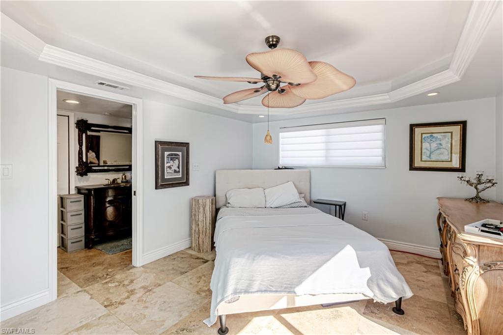Bedroom with ornamental molding, a ceiling fan, and a tray ceiling