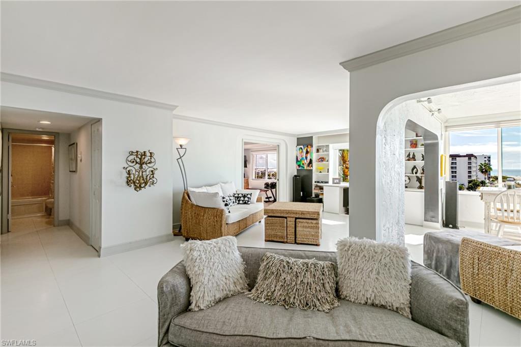 Living area featuring arched walkways, crown molding, healthy amount of natural light, and built in features