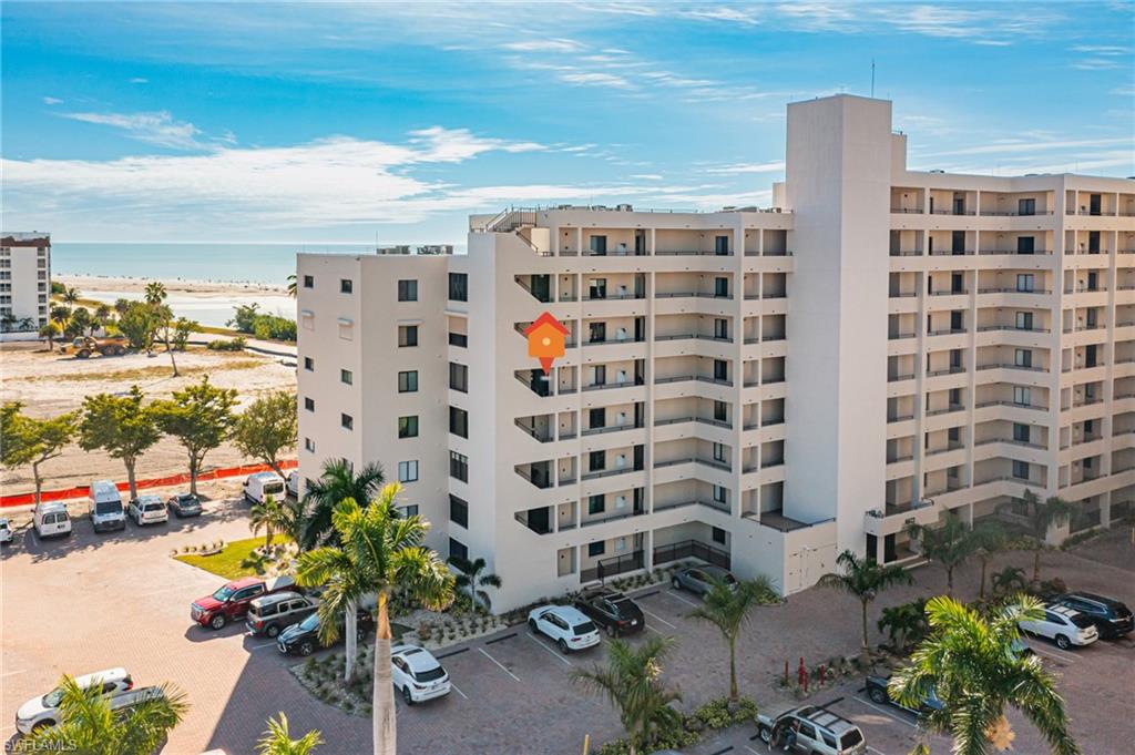 View of apartment building / complex featuring a water view and uncovered parking