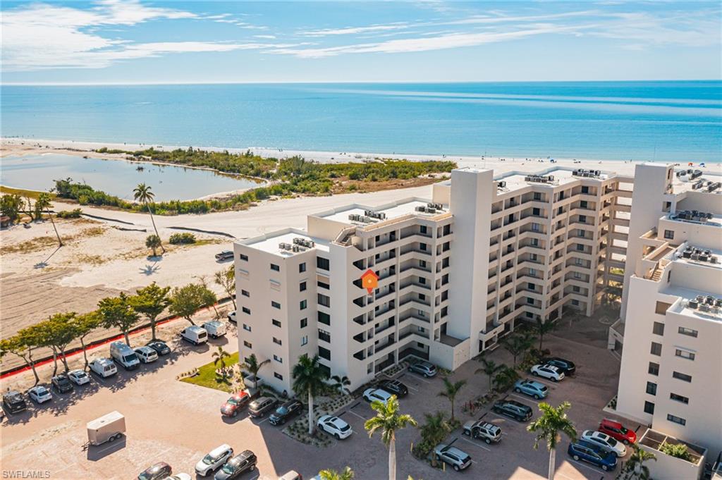 Drone / aerial view of apartment complex and waterfront with a beach