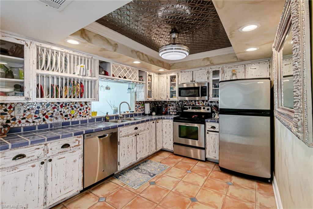 Kitchen with stainless steel appliances, crown molding, tile countertops, recessed lighting, and light tile patterned floors