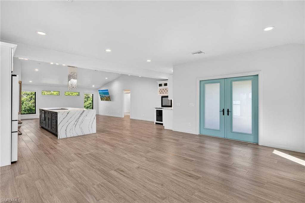 Featuring lofted ceiling, recessed lighting, french doors, and light wood floor.