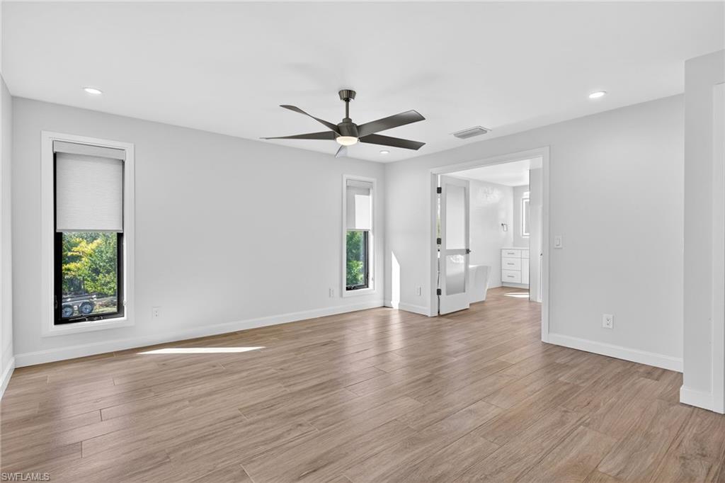 Primary bedroom en suite is open and airy, featuring vaulted ceilings and large windows.