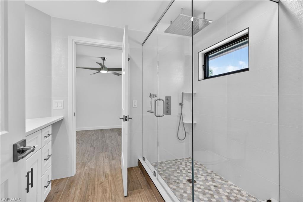 Full Jack and Jill bath featuring large tiled, rainfall shower stall, ample natural light.