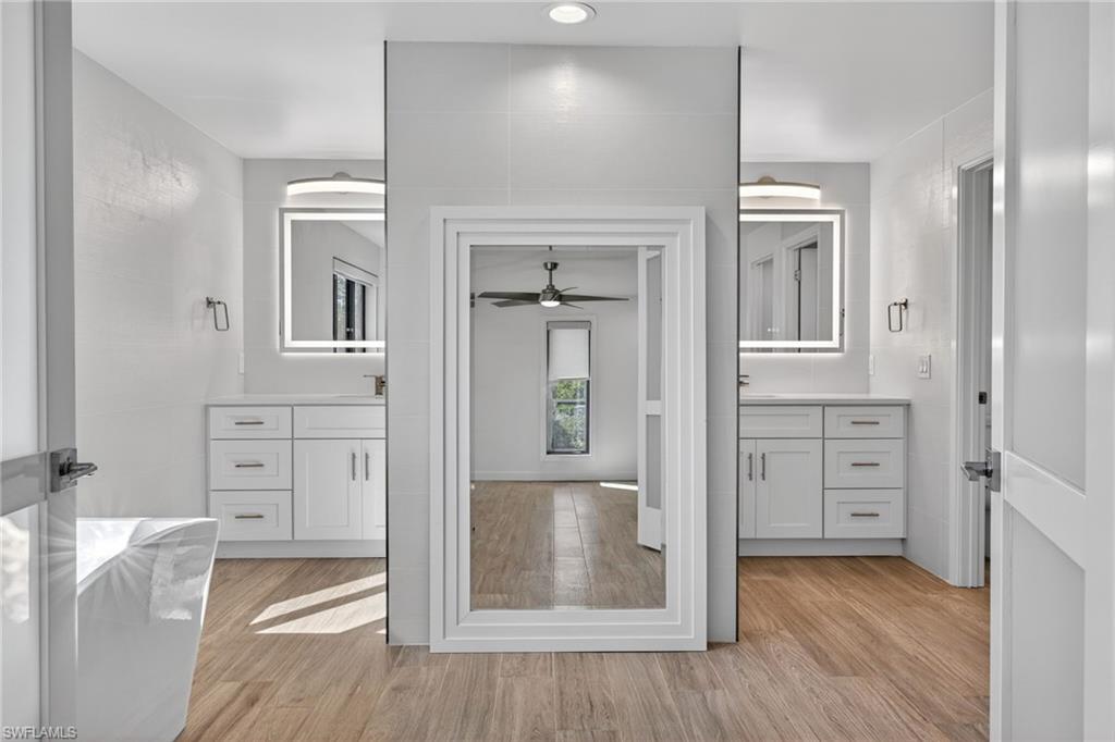 Fully renovated primary bathroom with well lit divided duel vanities and lots of natural light.