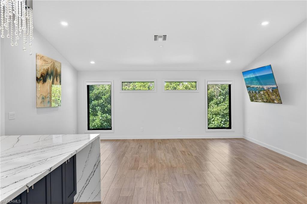 Spacious living area by kitchen with large windows and exceptional lighting.
