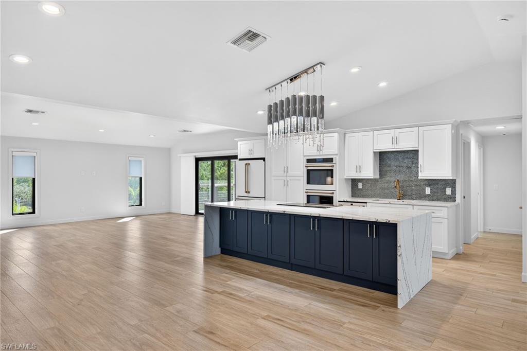 Spacious stone island, GE Cafe appliances, designer tile backsplash, and custom cabinetry.