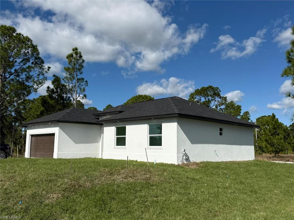 View of property exterior with an attached garage, stucco siding, and a lawn