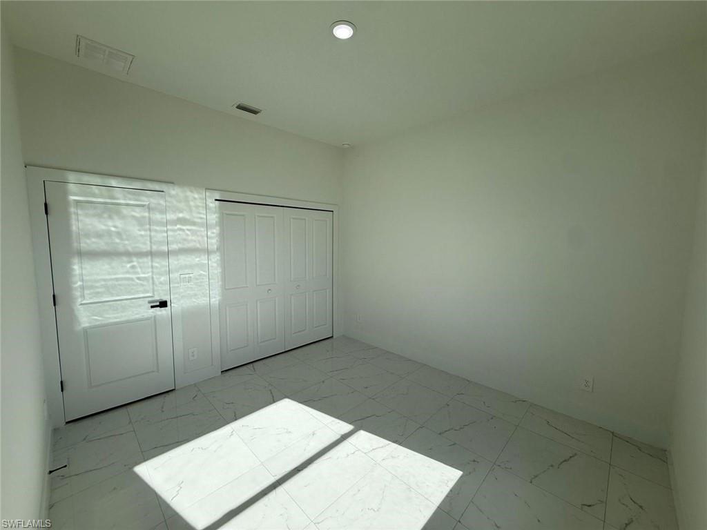 Unfurnished bedroom featuring a closet and light marble finish floors