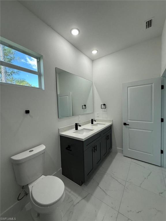 Full bathroom with double vanity and light marble finish floors