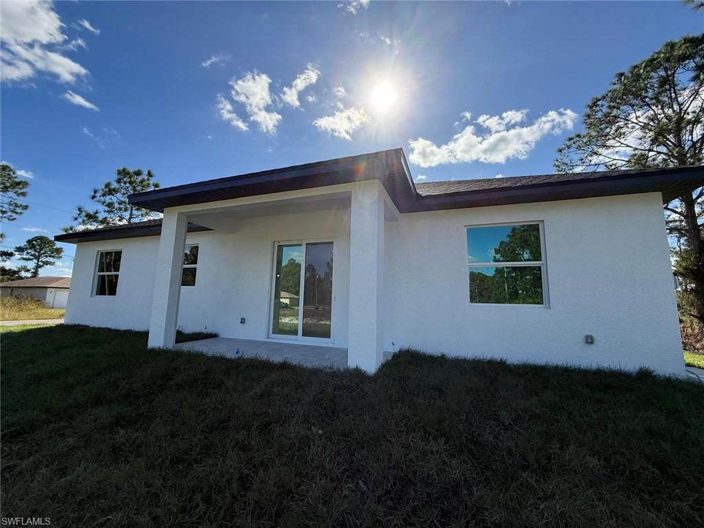 Back of house with a patio area, stucco siding, and a lawn