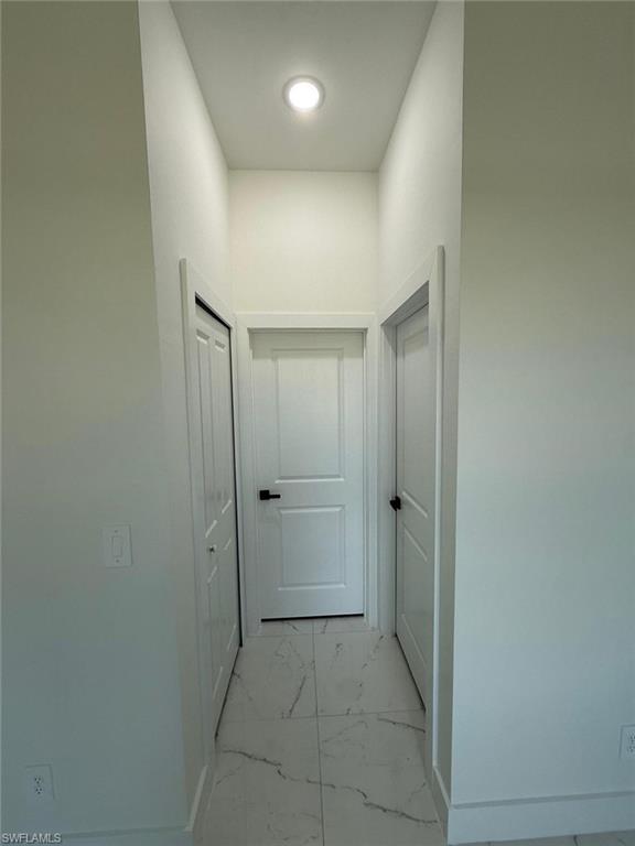 Hallway featuring light marble finish floors