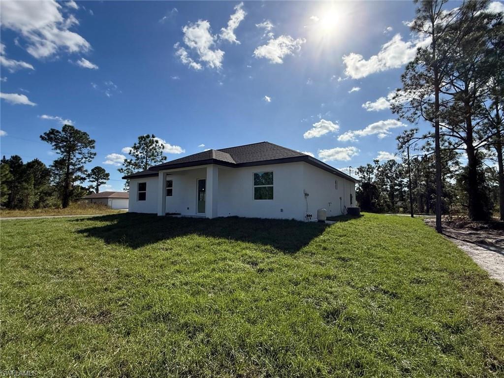 Rear view of property featuring stucco siding and a yard