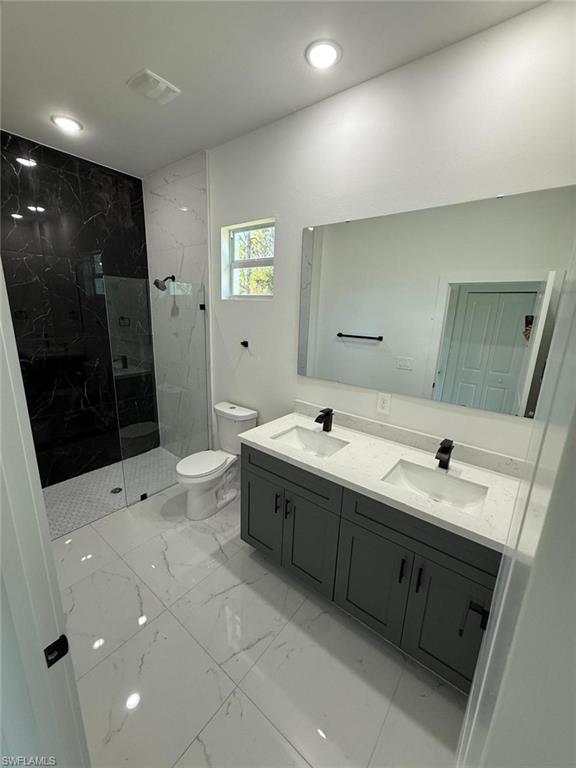 Bathroom with double vanity, a marble finish shower, light marble finish floors, and recessed lighting