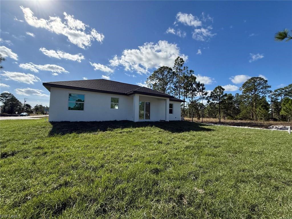 Rear view of property with stucco siding and a lawn