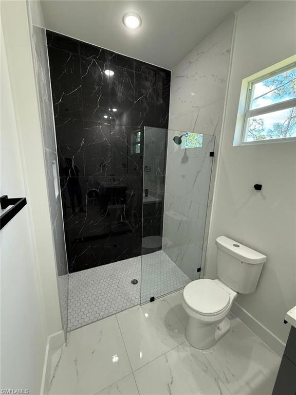 Bathroom featuring a marble finish shower, marble finish flooring, and vanity