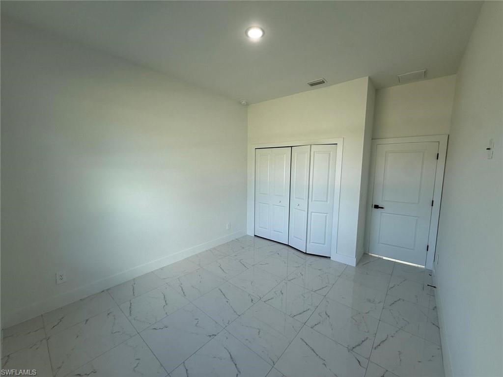 Unfurnished bedroom with light marble finish flooring and a closet
