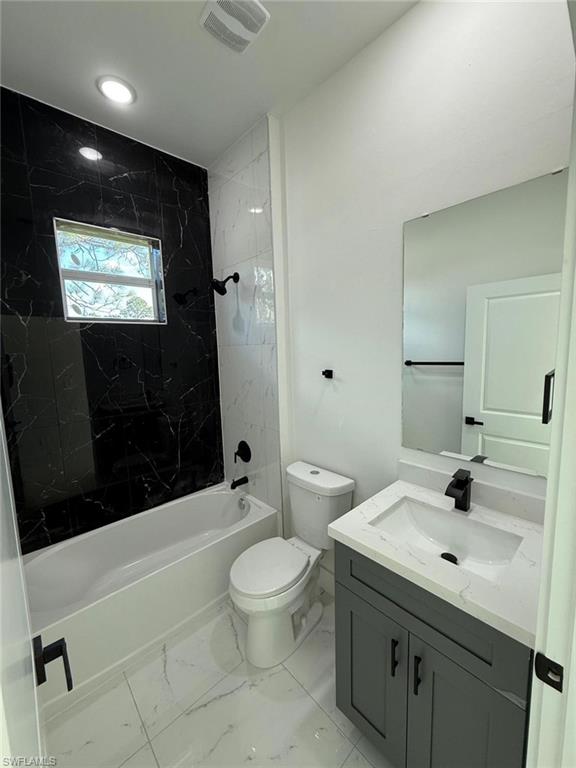 Bathroom featuring vanity, shower / tub combination, and light marble finish flooring