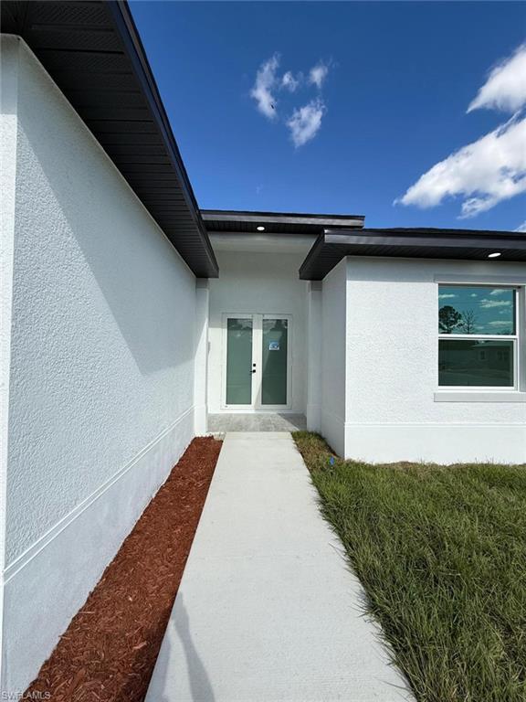 Entrance to property featuring stucco siding and french doors