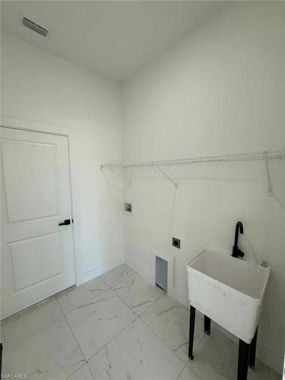 Laundry room with light marble finish flooring, hookup for a washing machine, and electric dryer hookup