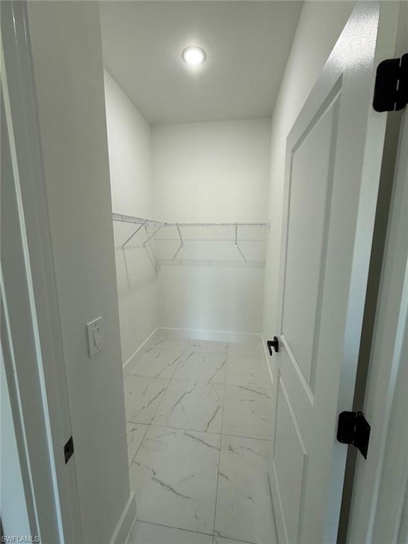 Spacious closet featuring light marble finish floors
