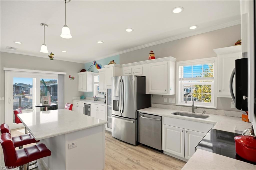 Kitchen featuring white cabinets, healthy amount of natural light, stainless steel appliances, recessed lighting, and ornamental molding