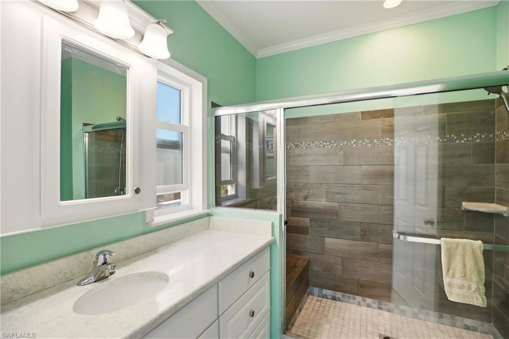 Bathroom featuring vanity, a stall shower, and crown molding