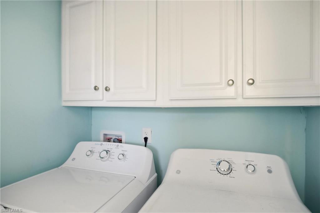 Washroom with washer and clothes dryer and cabinet space