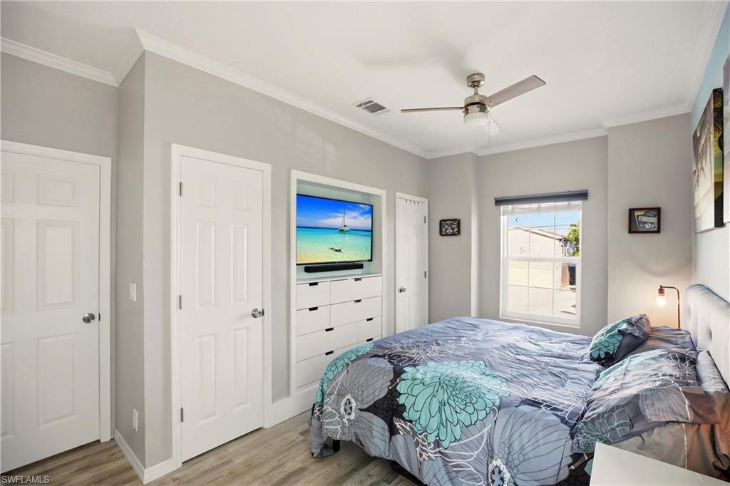Bedroom with crown molding, wood finished floors, and a ceiling fan