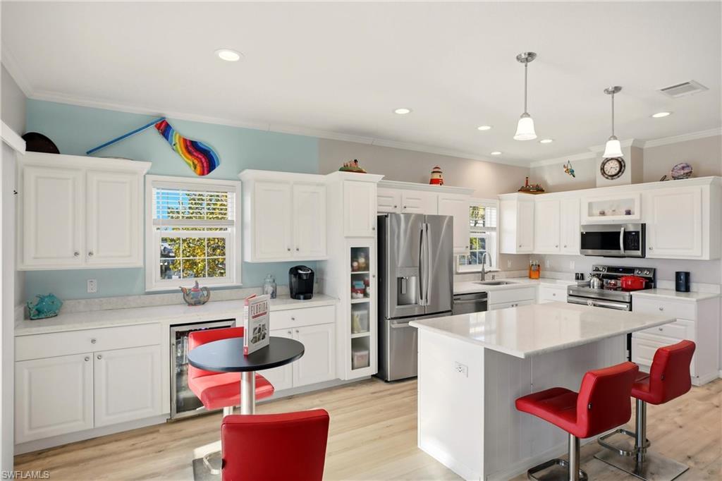 Kitchen with a breakfast bar area, white cabinetry, appliances with stainless steel finishes, light wood-style floors, and ornamental molding