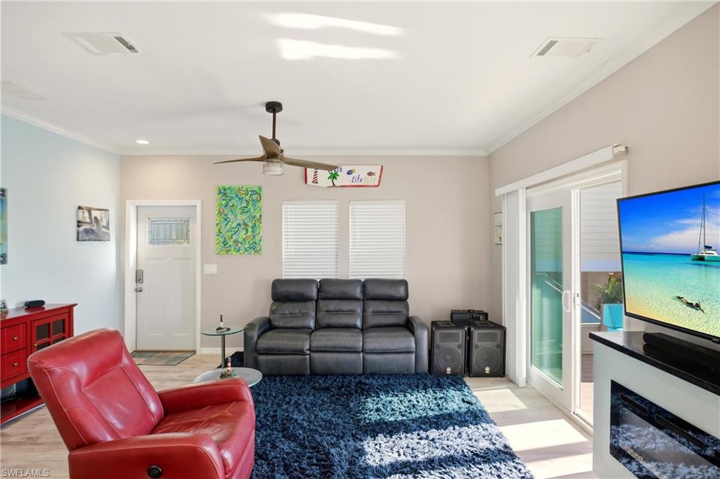 Living room featuring light wood-style flooring, ornamental molding, ceiling fan, and recessed lighting