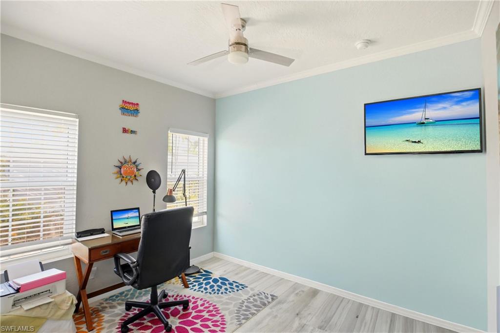 Home office featuring ornamental molding, light wood-type flooring, and ceiling fan