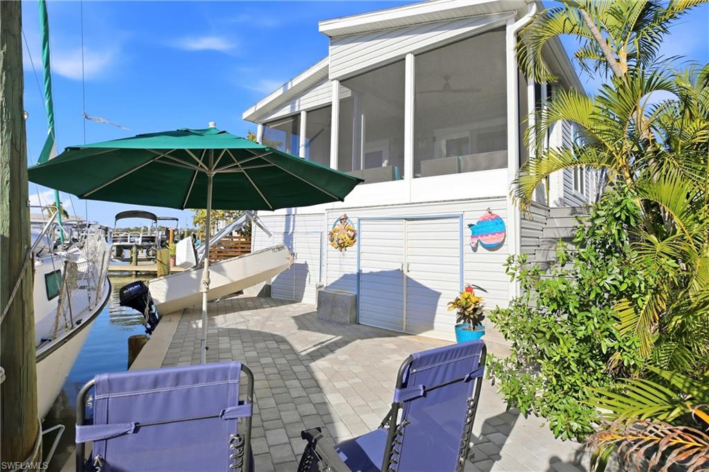 View of patio with a water view, a boat dock, and a sunroom