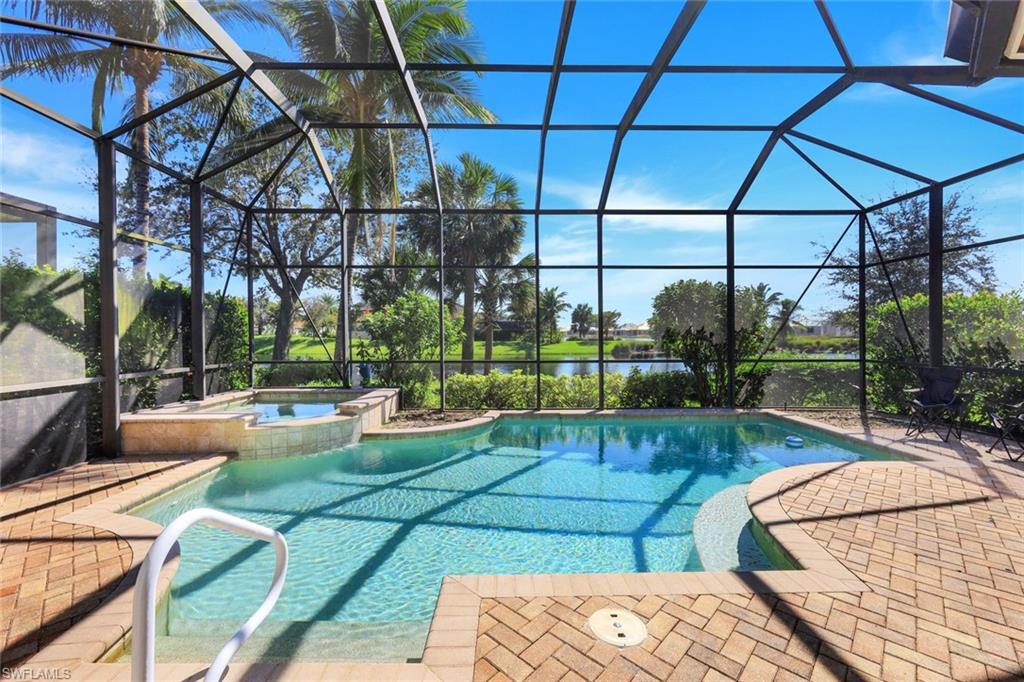 View of pool with an in ground hot tub, glass enclosure, and a patio