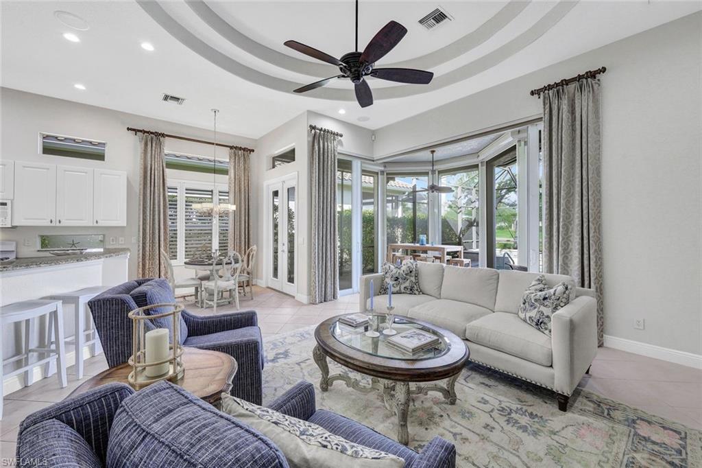 Living room with ceiling fan, light tile patterned floors, and a tray ceiling