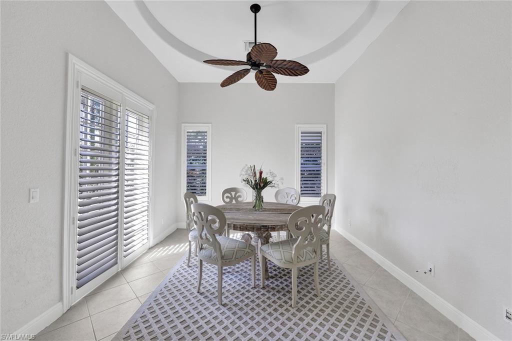 Dining space featuring ceiling fan, a wealth of natural light, light tile patterned floors, and a tray ceiling