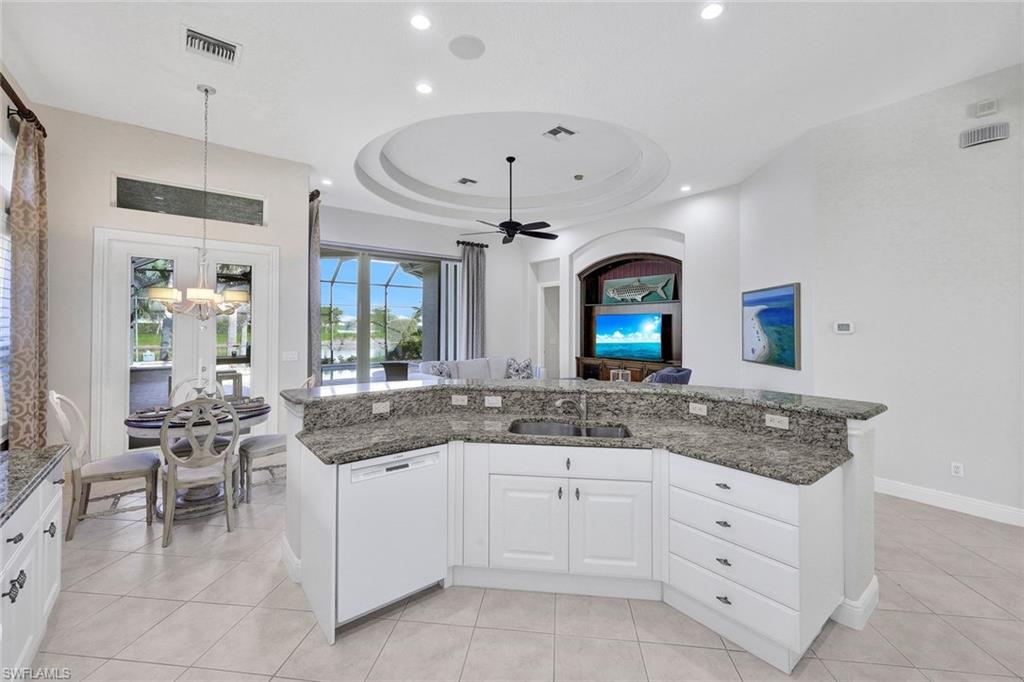 Kitchen featuring sink, a tray ceiling, dishwasher, and light tile patterned floors