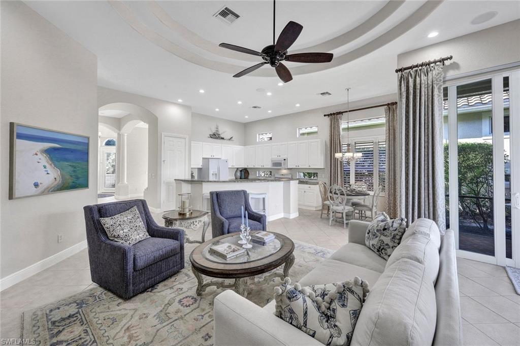 Tiled living room featuring ceiling fan and a raised ceiling