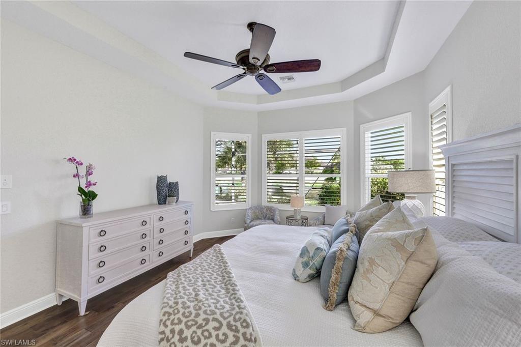 Bedroom featuring dark hardwood / wood-style flooring, a tray ceiling, and ceiling fan