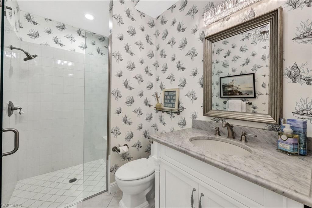 Bathroom featuring tile patterned flooring, toilet, vanity, and walk in shower