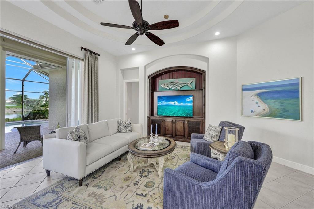 Tiled living room featuring ceiling fan and a tray ceiling