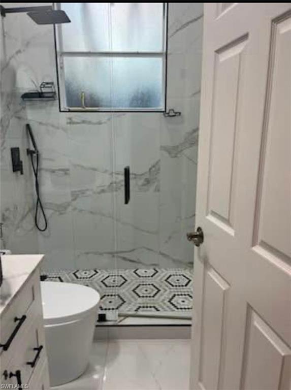 Bathroom featuring vanity and a marble finish shower