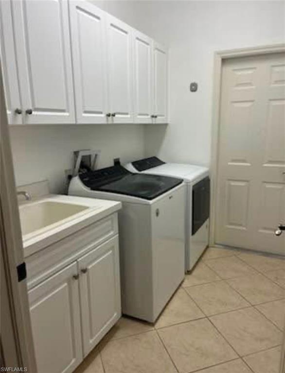 Laundry area with cabinet space, light tile patterned flooring, and washing machine and clothes dryer