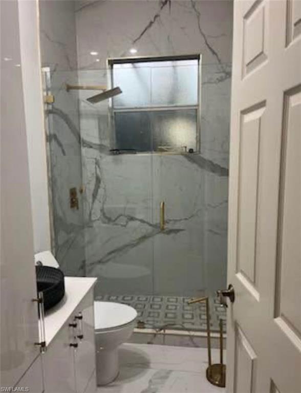 Full bathroom with vanity, a marble finish shower, and marble look tiles